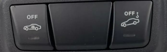 Zwei quadratische Tasten nebeneinander in einer dunklen Konsole: links ein Auto mit Wellenlinien darin und dem Wort OFF, rechts ein Auto mit einem Haken darüber und OFF