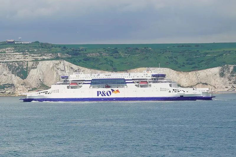 Fähre von P&O Ferries mit weißem Rumpf, blauem Band und dem P&O-Logo vor den weißen Kreidefelsen von Dover