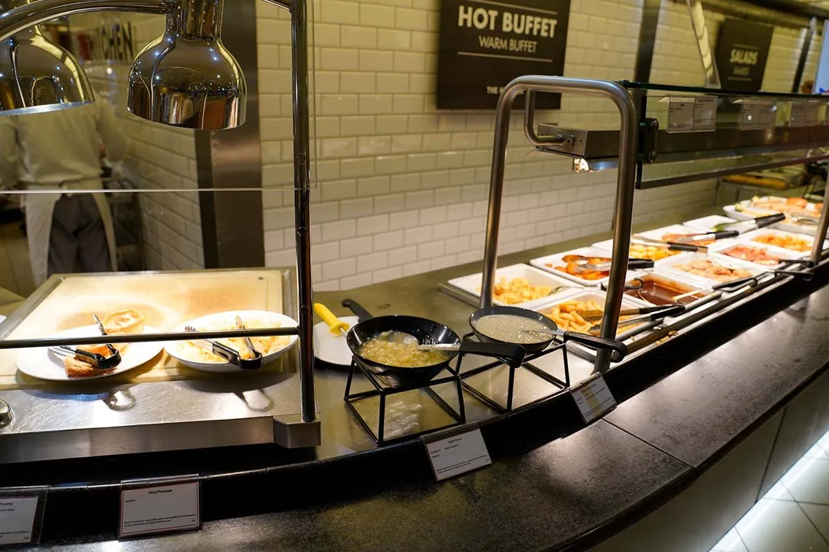 Die Buffetlinie an Bord unter dem Schild Hot Buffet, mit Wärmelampen und noch einigen Schalen Essen
