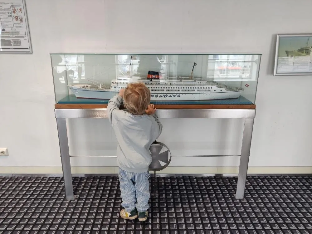 Ein kleines Kind schaut in eine Vitrine mit einem Modell eines älteren Seaways-Schiffs an Bord