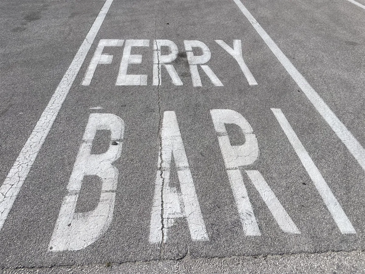 Fahrbahnmarkierung mit dem Text Ferry Bari auf dem Asphalt des Kais in Dubrovnik