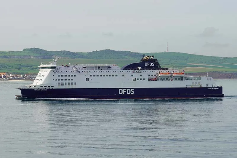 Die Côte des Flandres von DFDS, dunkelblau und weiß, an einer grünen Küste entlang