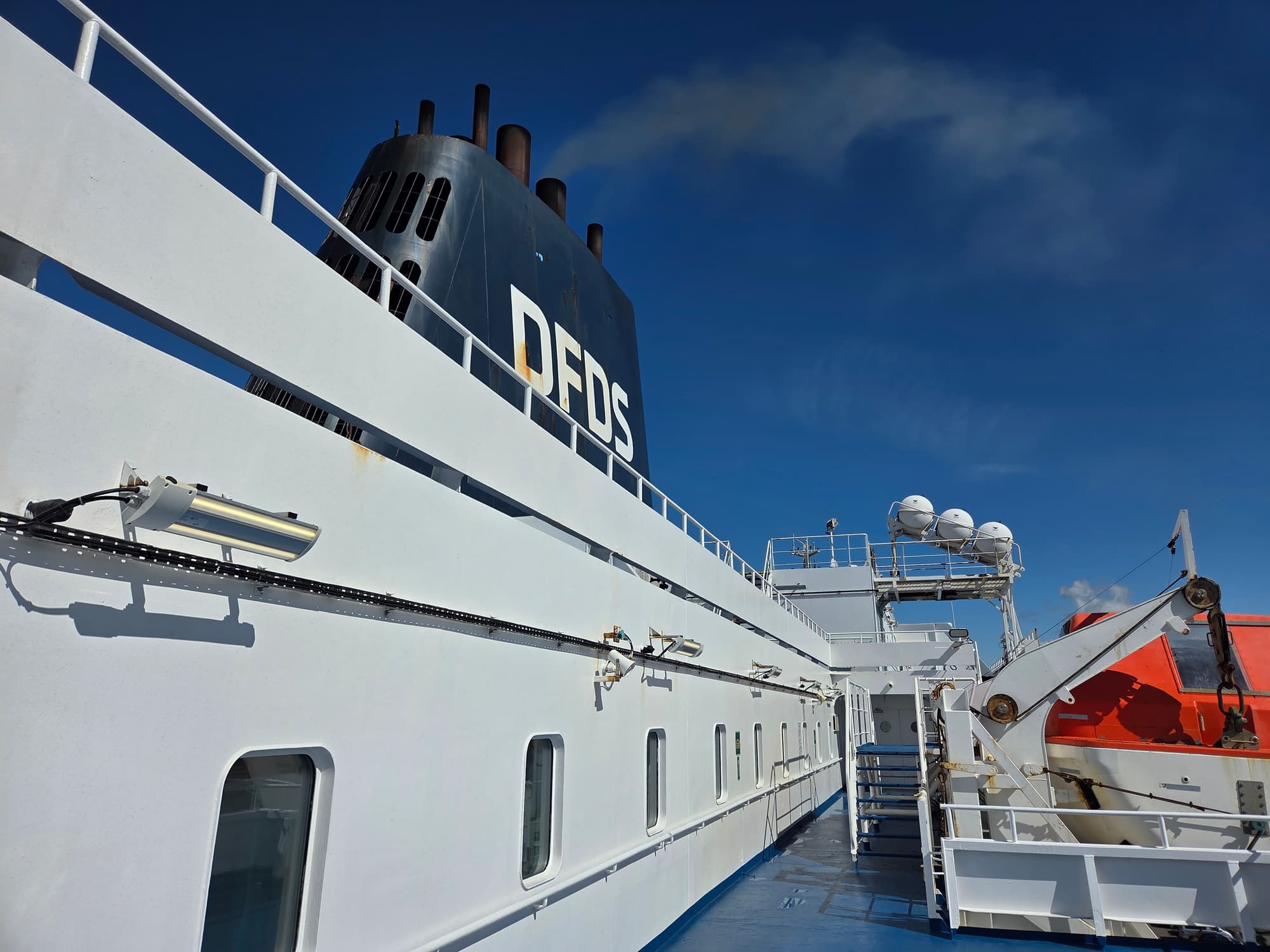 Das weiße Oberdeck der Delft Seaways mit dem schwarzen DFDS-Schornstein, unter blauem Himmel