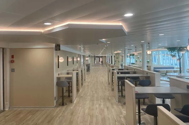 Deck an Bord von P&O Ferries mit hellem Holzboden, Esstischen mit Barhockern in Nischen und Fenstern auf der rechten Seite