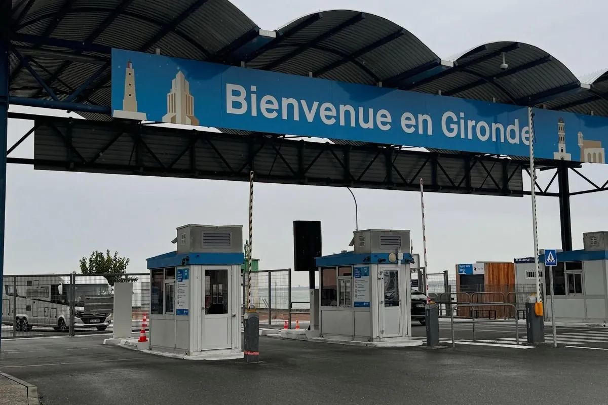 Zwei kleine Kassenhäuschen mit Schranken unter einem Dach mit dem Schild Bienvenue en Gironde, links ein Wohnmobil in der Warteschlange