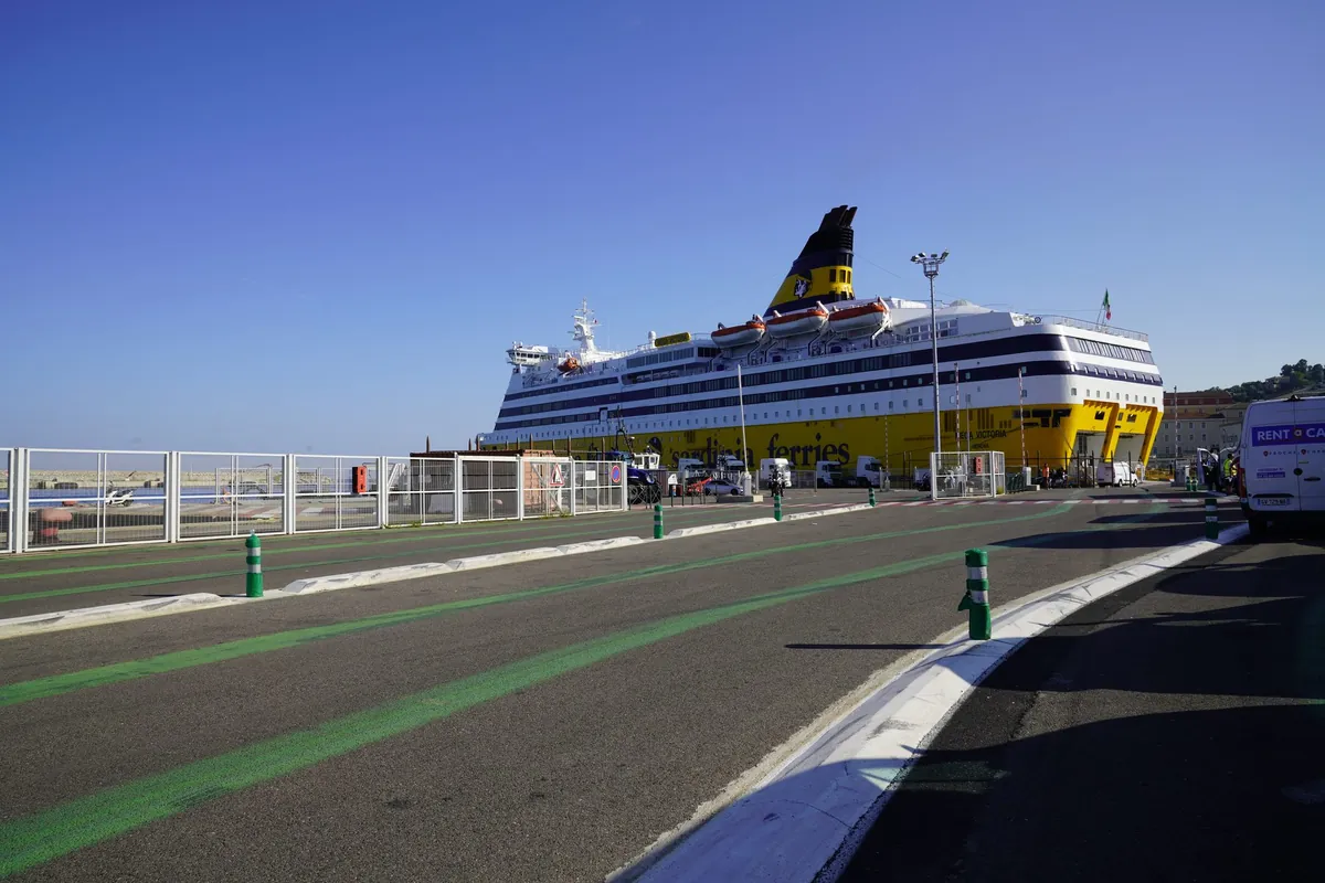 Die Fähre Mega Victoria von Corsica Ferries mit gelbem Rumpf und dunkelblauem Schornstein am Kai in Bastia, gesehen von der Aufstellfläche